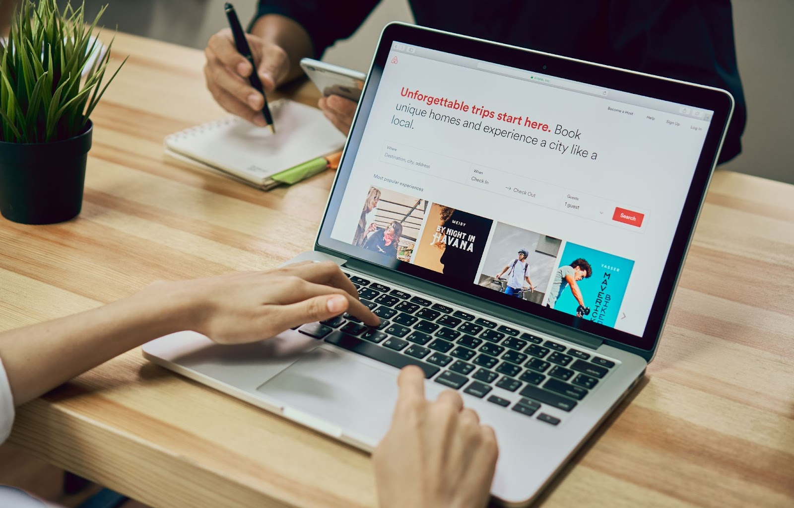 Hands typing on a laptop showing the Airbnb booking page.