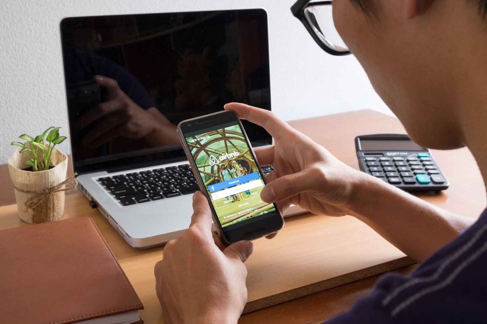 Person using Airbnb app on phone at a desk.